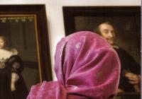 A woman in a headscarf views portraits in a Dutch museum