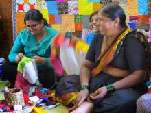 women weaving colorful fabrics and laughing together