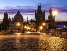 An image of a beautifully lit Prague street overlooking monuments and castles at dusk