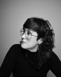 a person with brown hair, glasses, in a black turtle neck