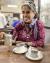 Dr. Anu pouring a cup of chai from a silver tea kettle.