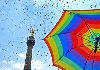 Rainbow flag umbrella in front of tower